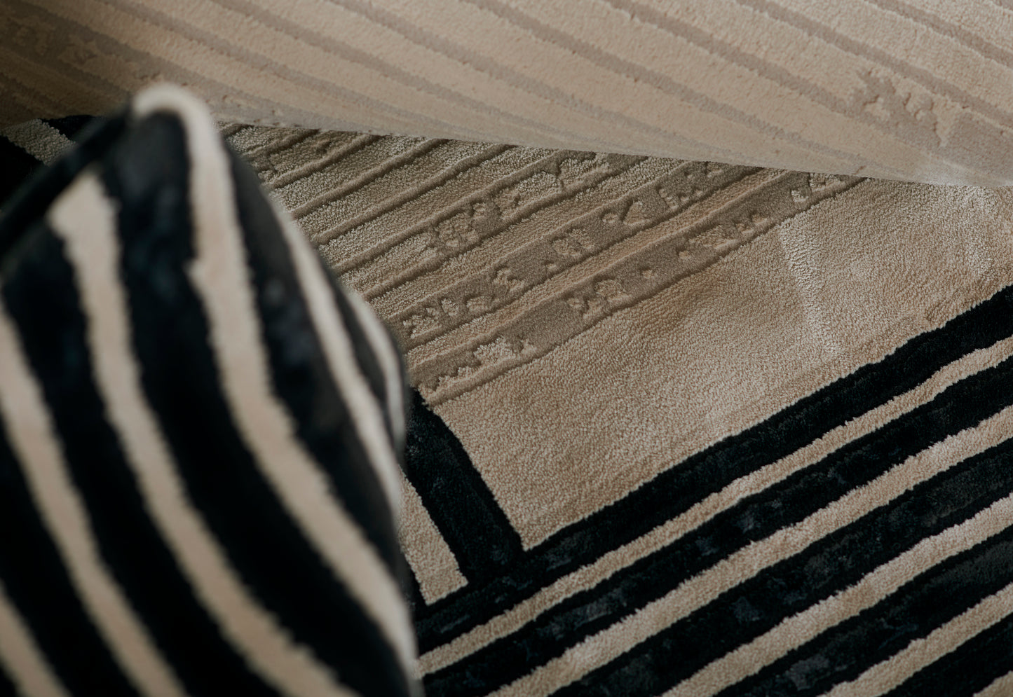 Close-up of a woven beige runner rug with bold black stripes and a black-and-white striped fabric draped in the foreground.