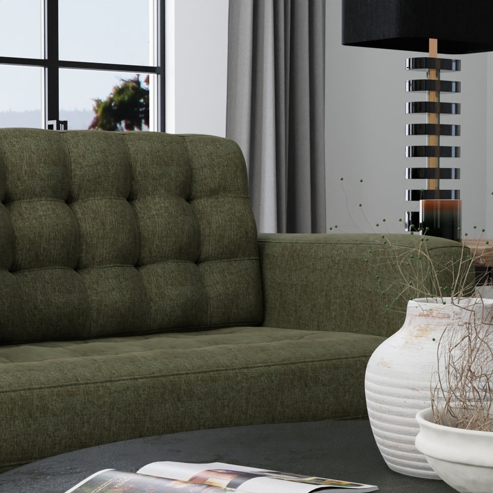 Olive green tufted fabric sofa in a modern living room with a striped black lamp and white ceramic vases.