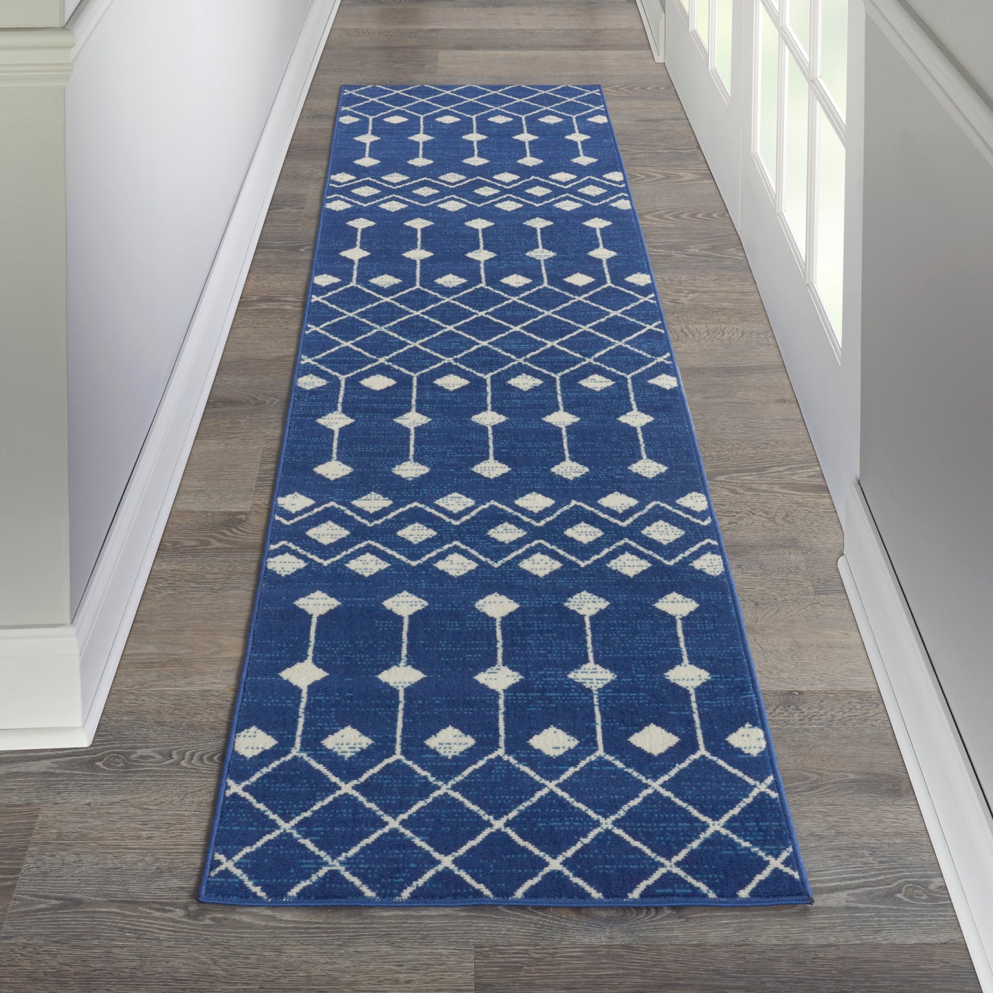 Blue woven runner rug with white geometric diamonds and lattice pattern in a hallway.