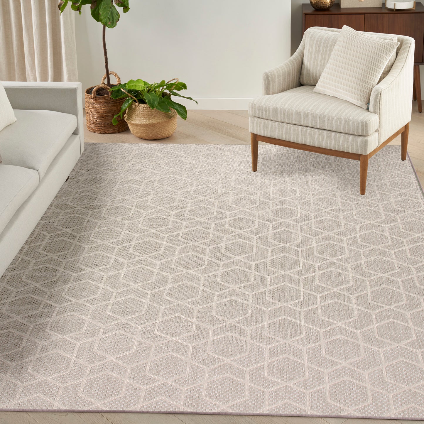 Neutral beige area rug with a white geometric lattice pattern in a bright living room beside a striped armchair.