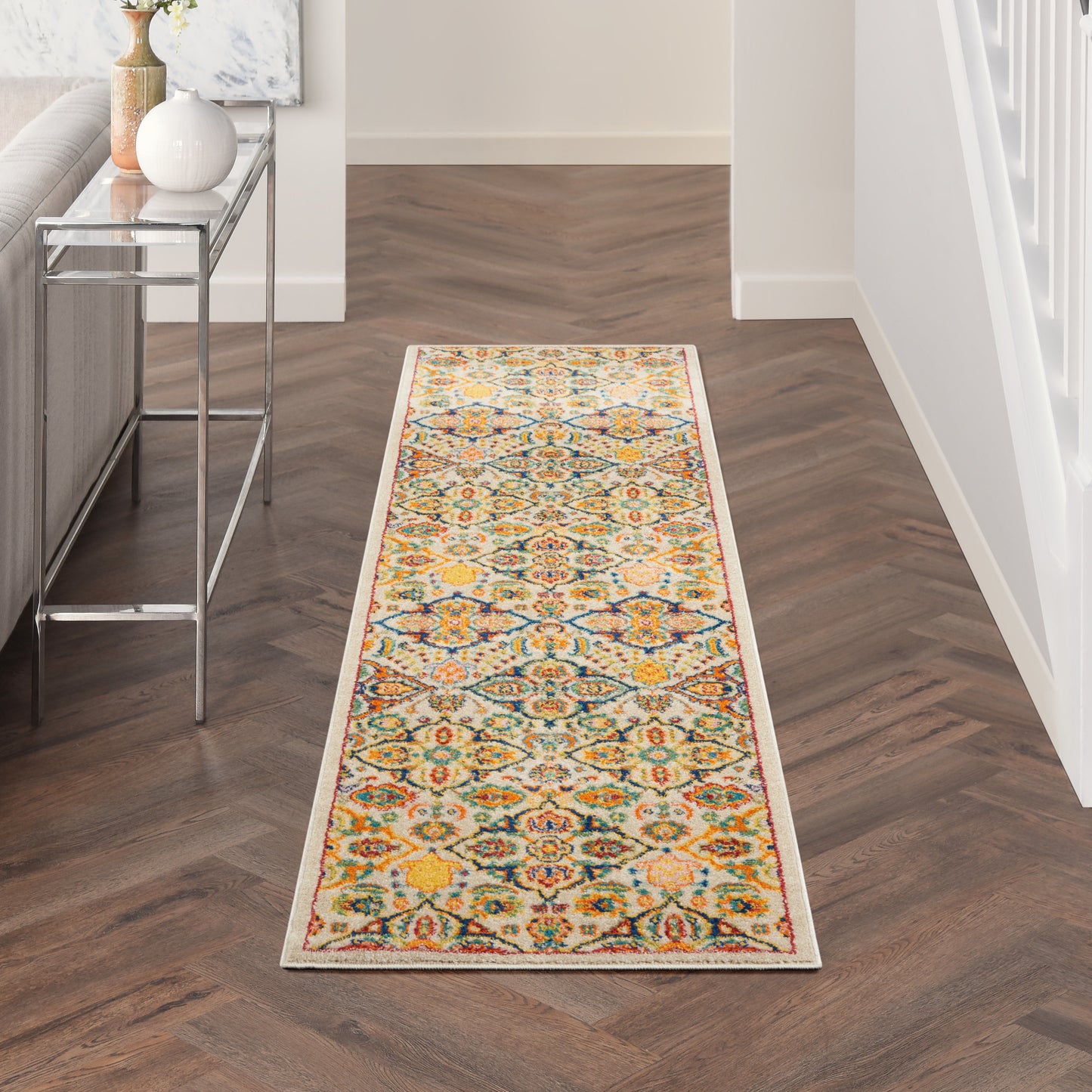 Long oriental-style runner rug in yellow, teal, orange and cream tones in a modern hallway with a metal console table.