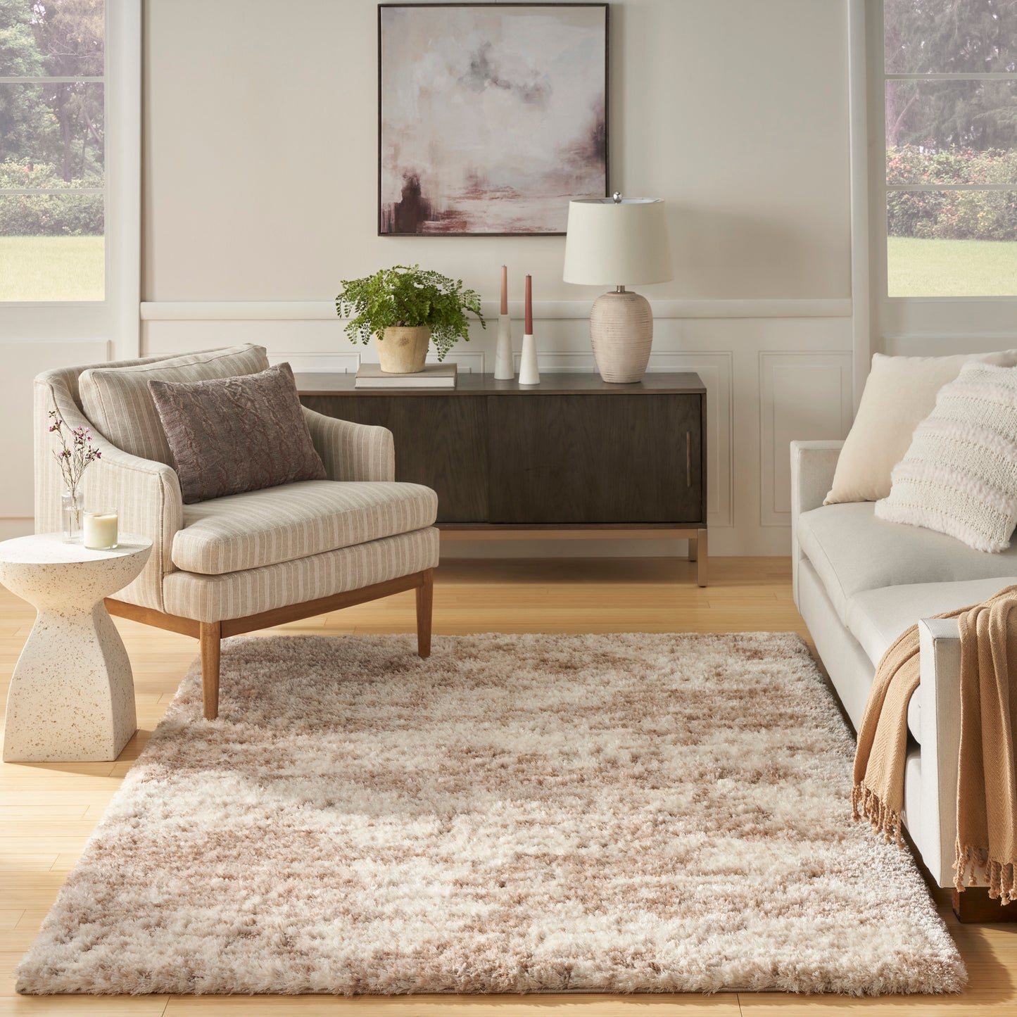 Soft beige and cream shag rug in a neutral living room with a light gray sofa, beige armchair, and dark wood console.
