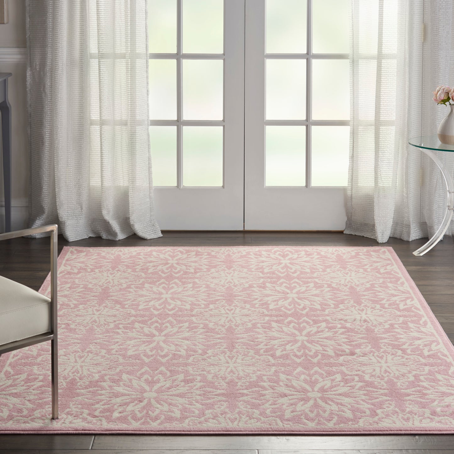 Pink patterned area rug with white floral motif in a bright room with French doors.
