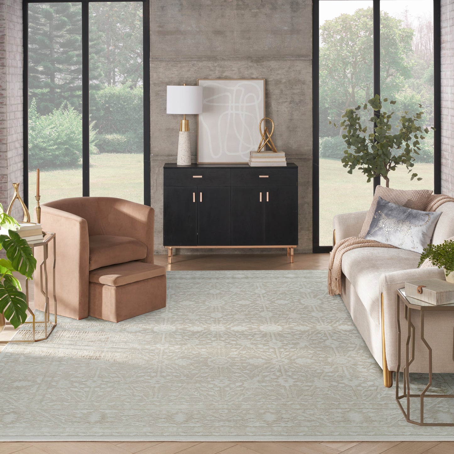 Neutral living room with large windows, black cabinet with gold handles, beige armchairs, light rug and abstract art.