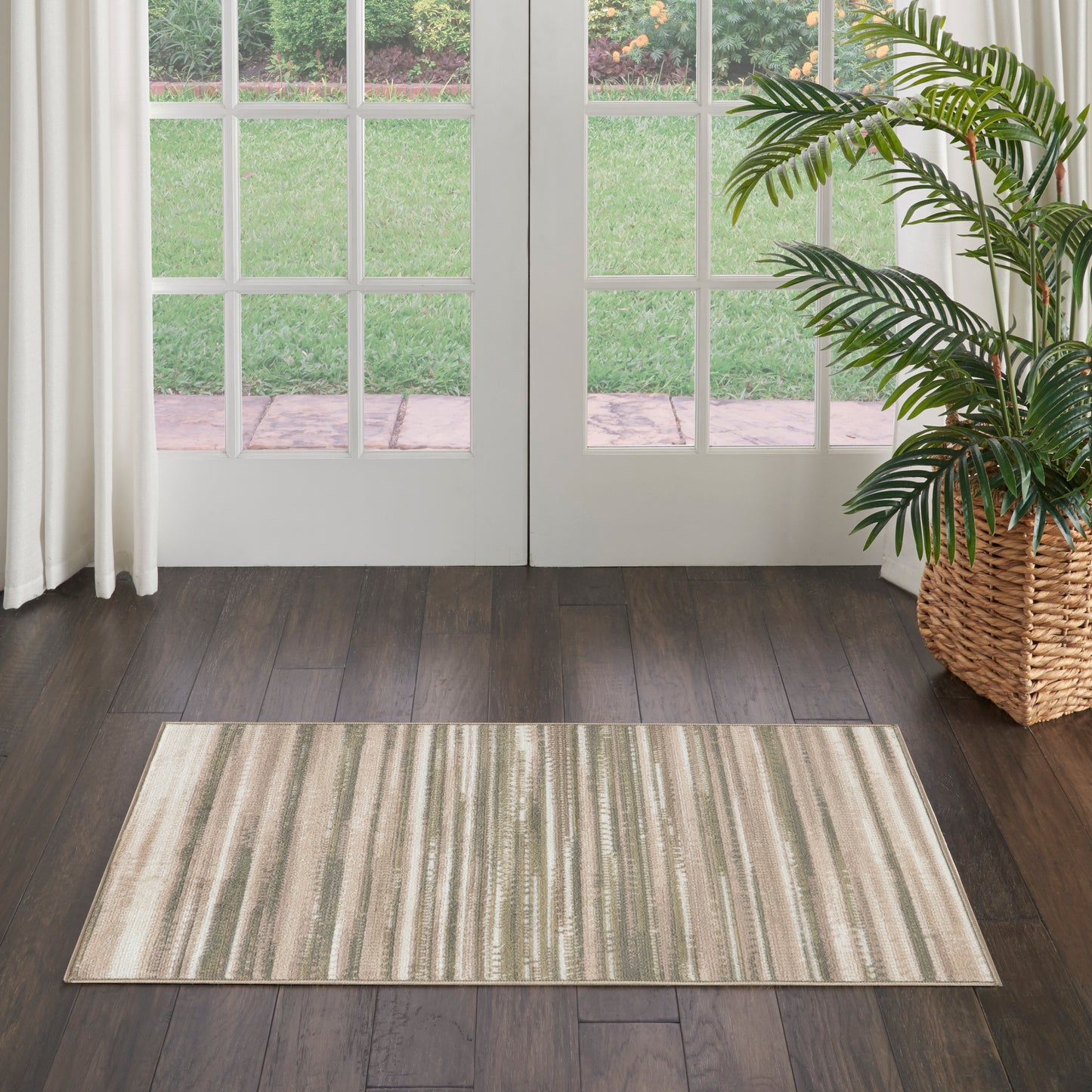 Rectangular striped beige-taupe rug on dark hardwood floor beside glass-paned French doors and a wicker plant basket.