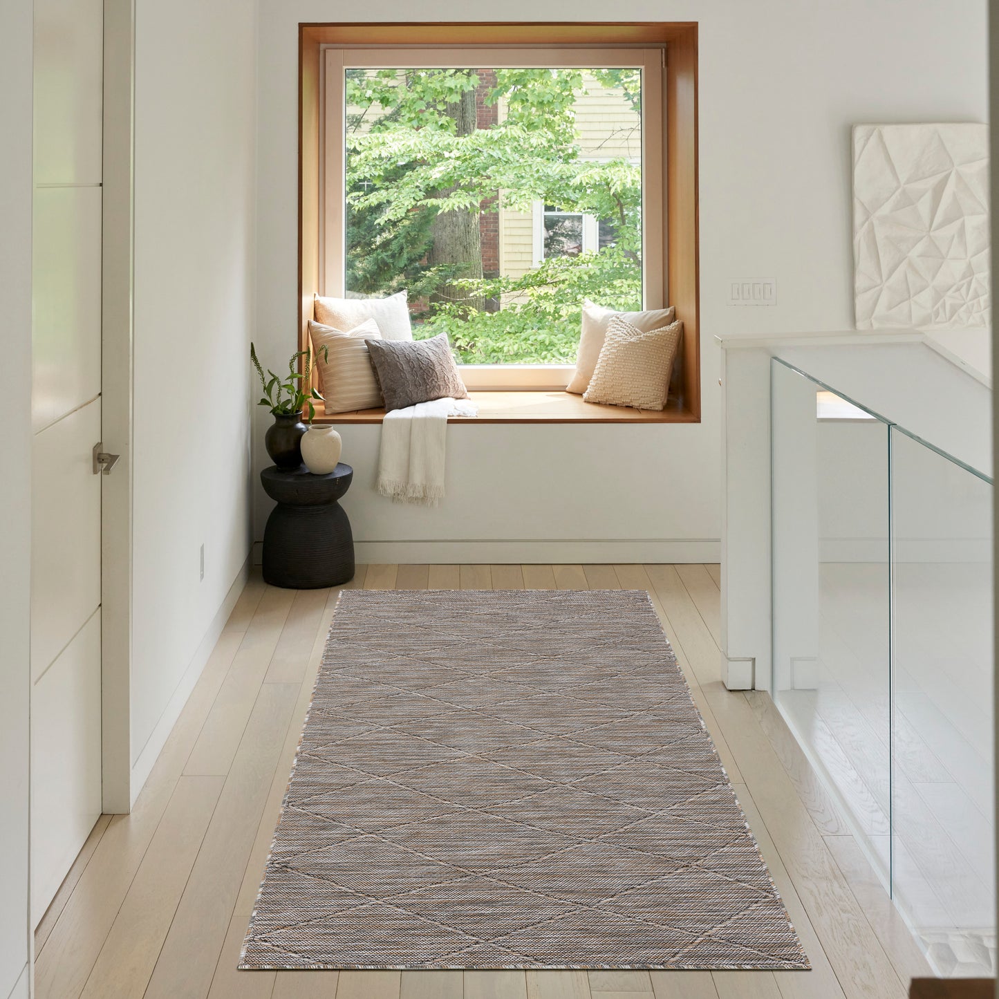 Soft gray woven runner rug with a subtle diamond pattern in a bright hallway by a window seat.