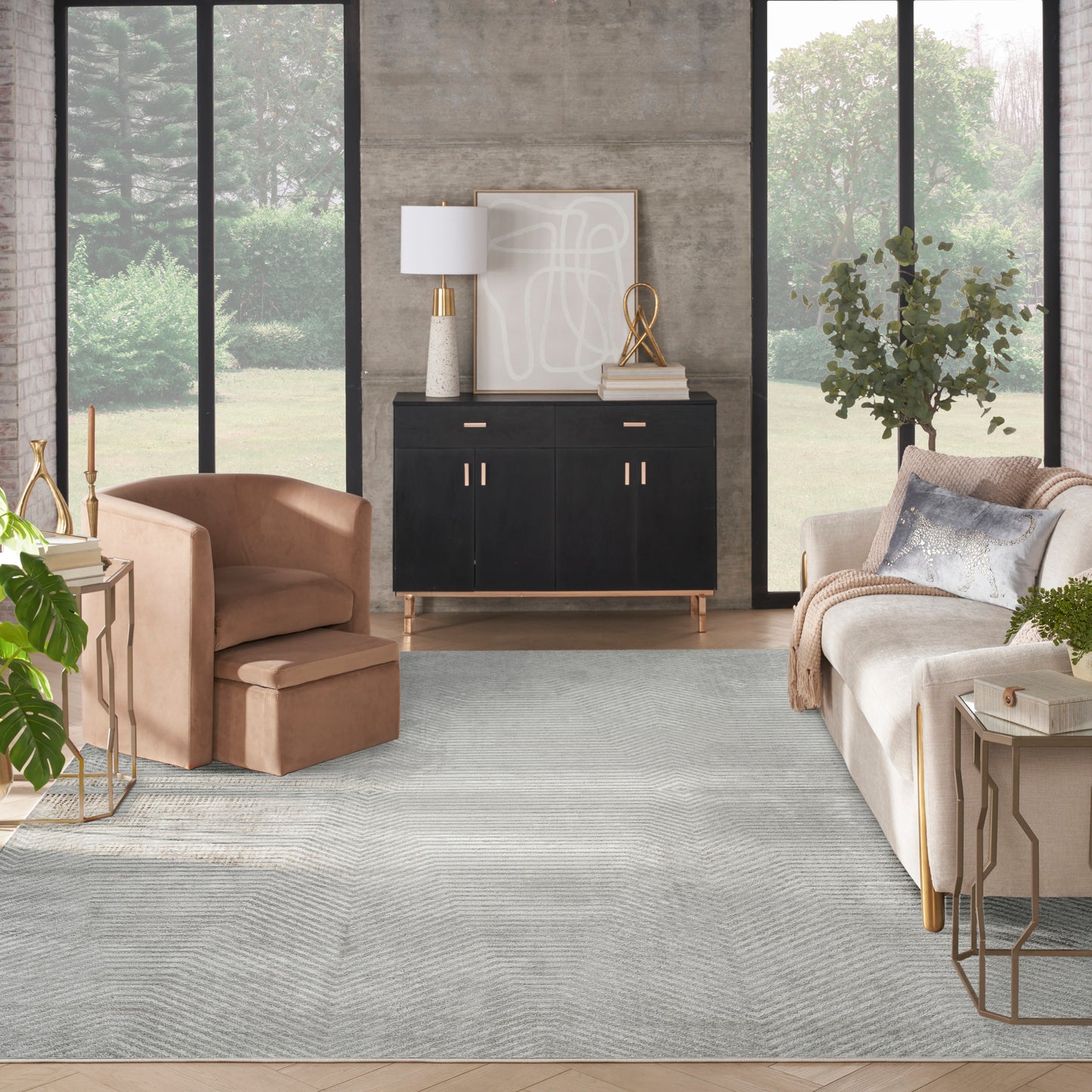 Vintage 8' x 10' rug in a modern living room with a peach velvet armchair, beige sofa, black sideboard, gold accents, and large windows.