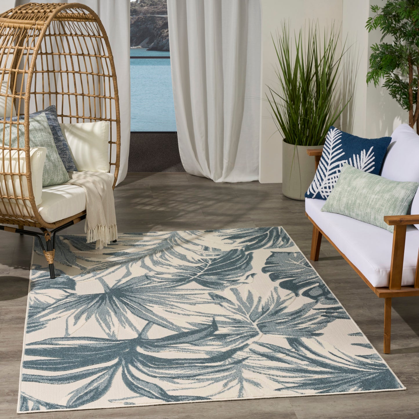 Teal palm-leaf patterned rug on ivory base; woven textile for boho coastal living room decor.