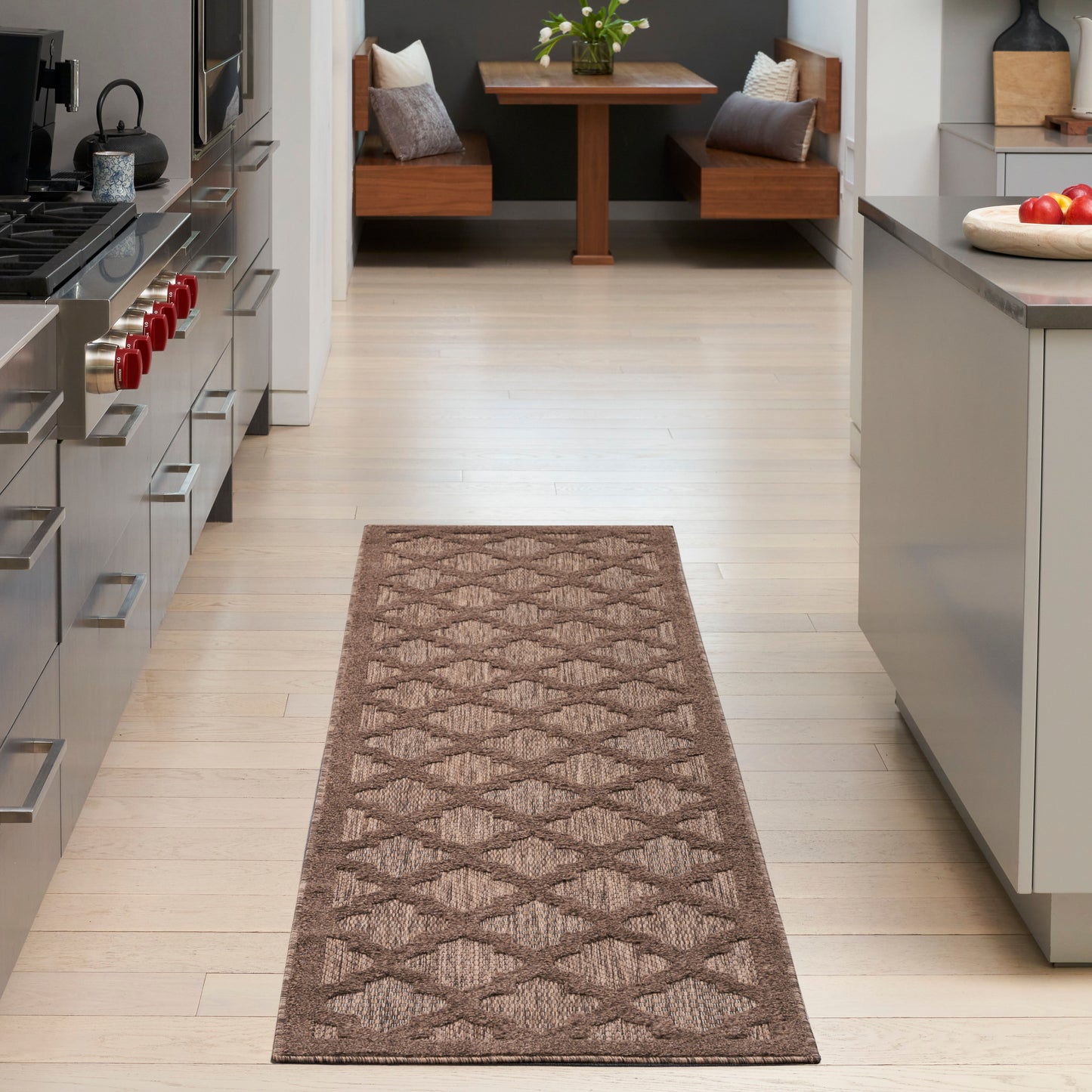 Long rectangular brown geometric runner rug on light wood floor, leading to dining nook in a modern kitchen.