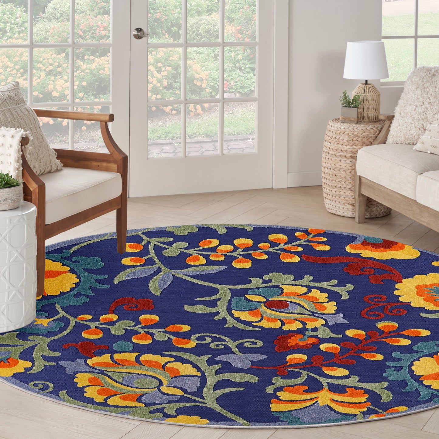 5' round navy outdoor rug with a bright yellow, orange, red, and green floral scroll pattern.