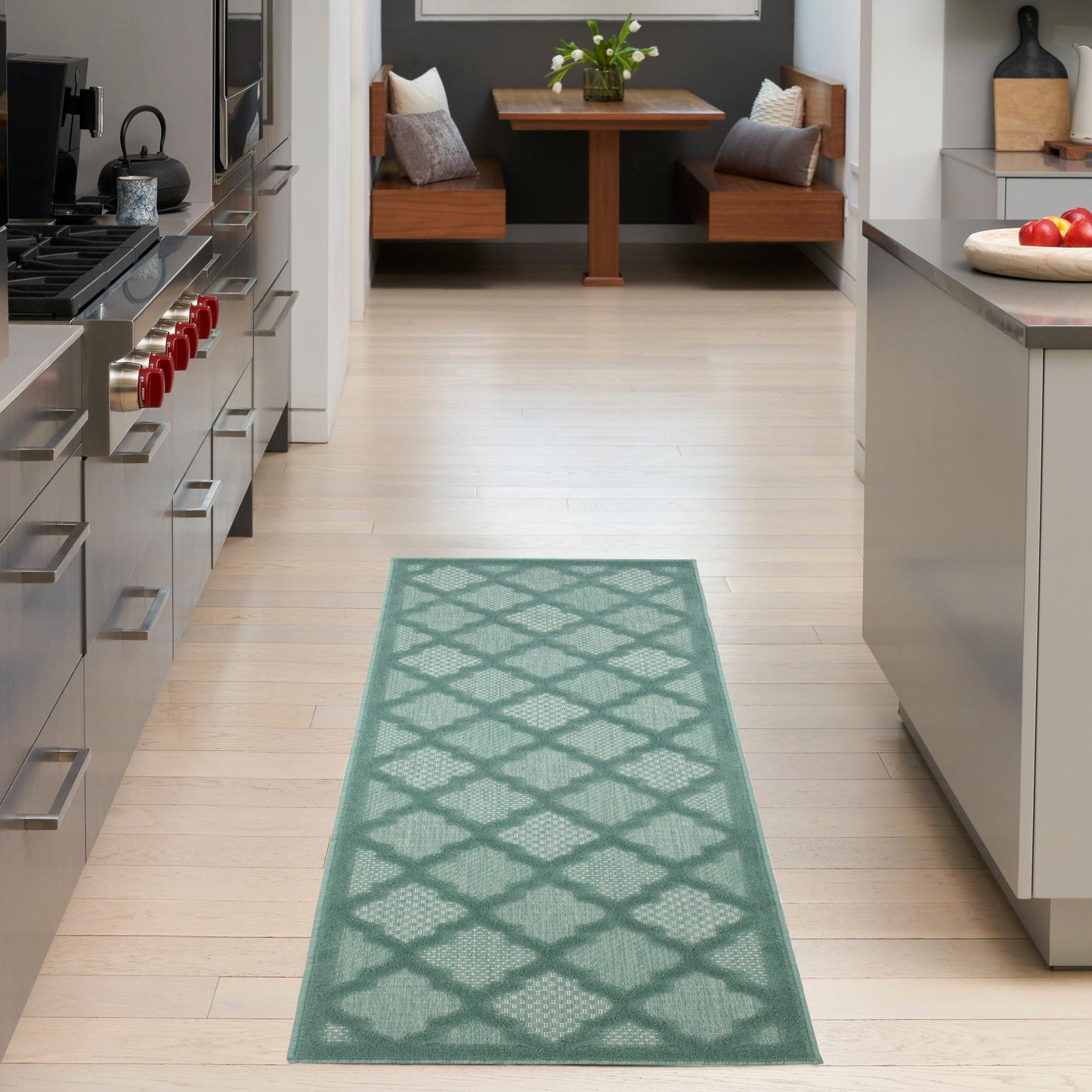 Teal lattice-pattern rug runner in a bright modern kitchen with light wood floor and stainless appliances.
