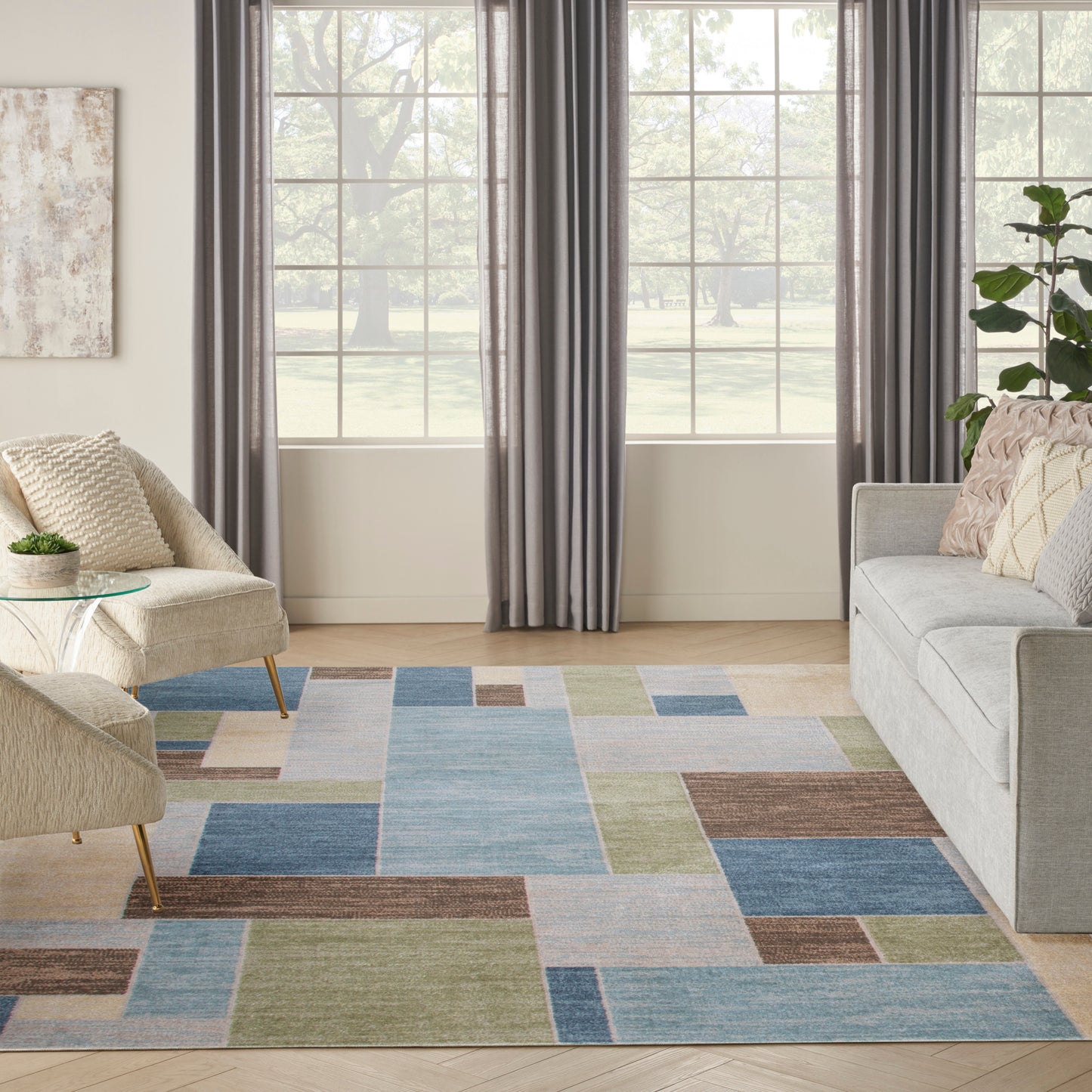 Geometric color-block rug in blues, greens, beige and brown; light gray sofa, beige chair, glass coffee table, gray curtains.