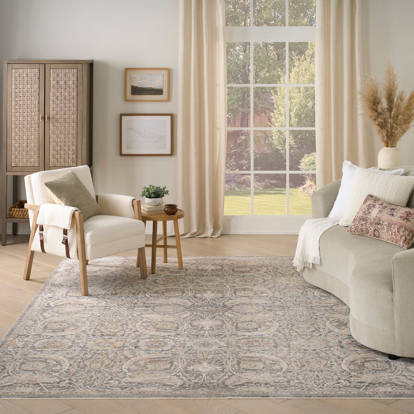 Neutral living room with beige sofa, wooden-frame armchair, side table, woven cabinet, wall art, window, and blue-gray rug.