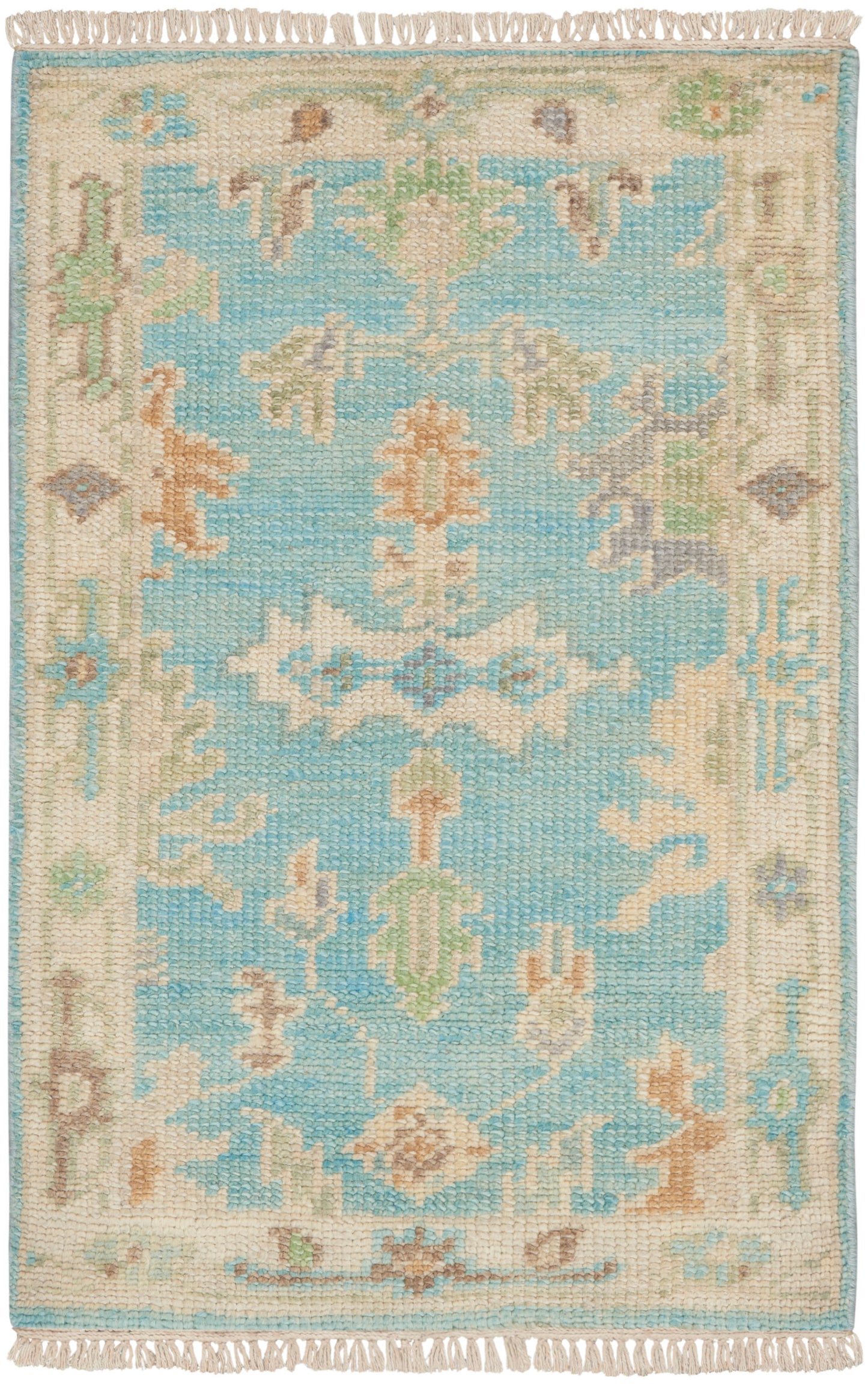 Rectangular woven rug with turquoise center, cream-beige border, pastel floral motifs and fringed ends.