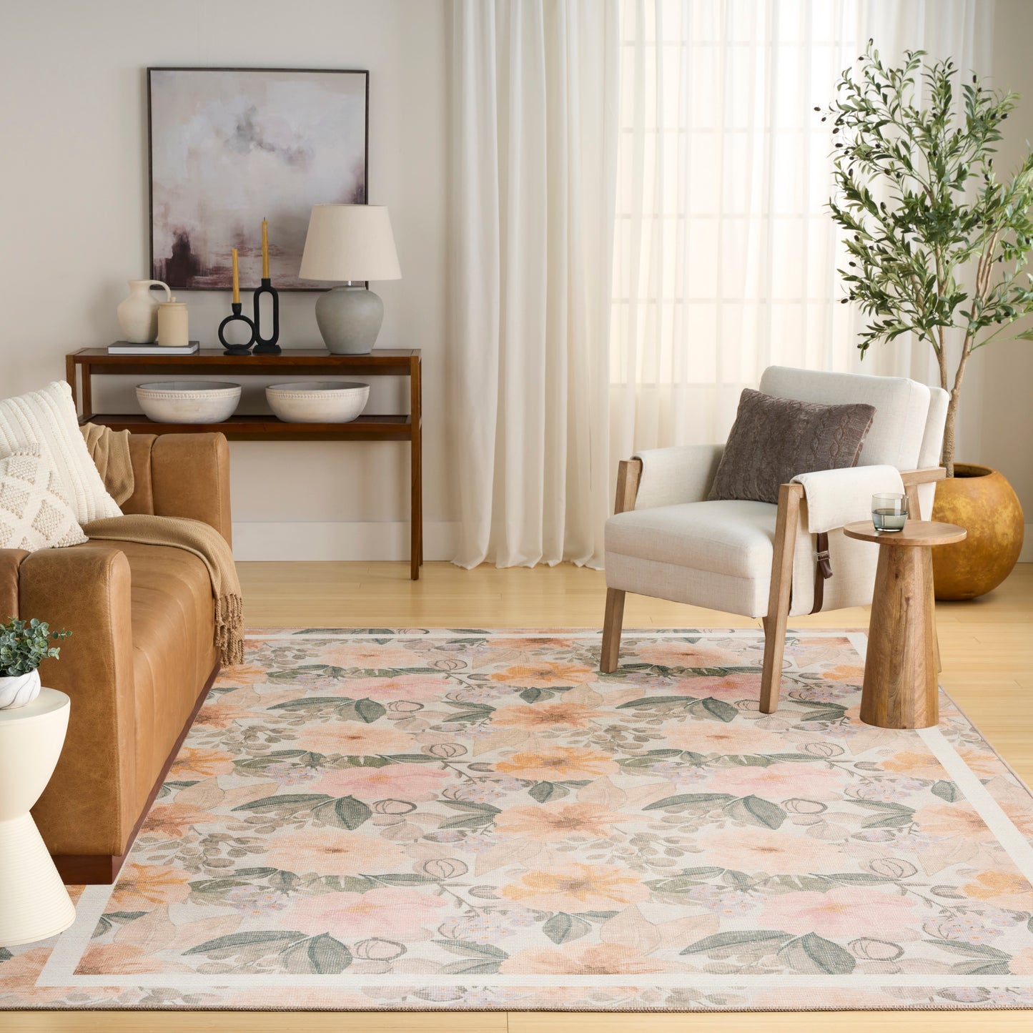 Pastel floral area rug in a cozy living room with a brown leather sofa, white armchair, wood console table and potted plant.