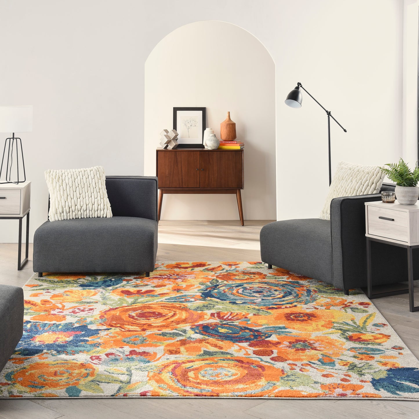 Cozy living room with dark gray modular sofas, a vibrant orange-blue rug, an arched doorway, and a wooden sideboard.