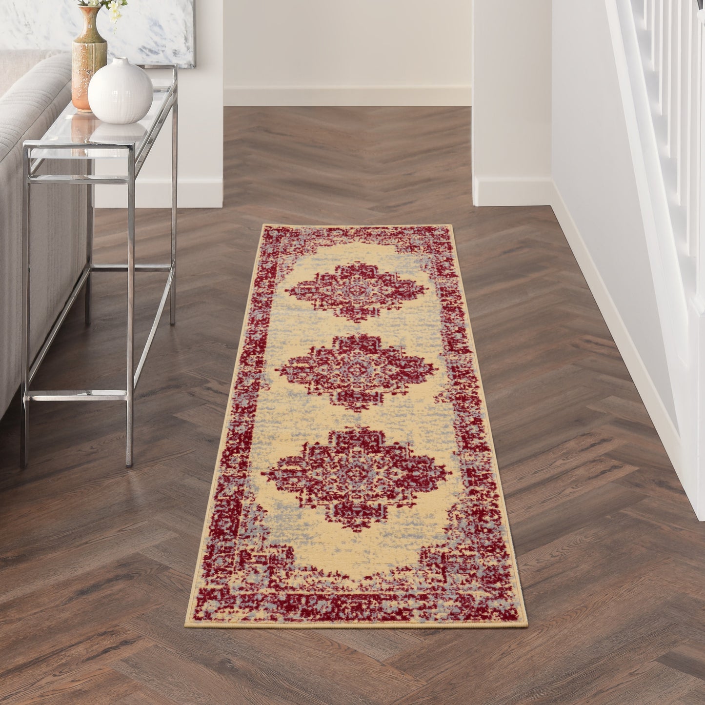 Beige oriental runner rug with three maroon medallions and an ornate red border in a modern hallway.