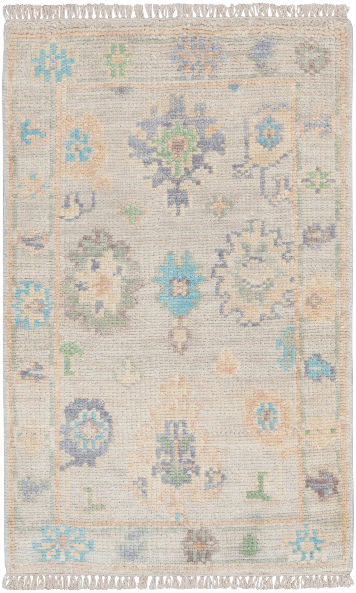 Pastel floral rug with beige base, blue, mint, and peach motifs; fringed ends and decorative border.