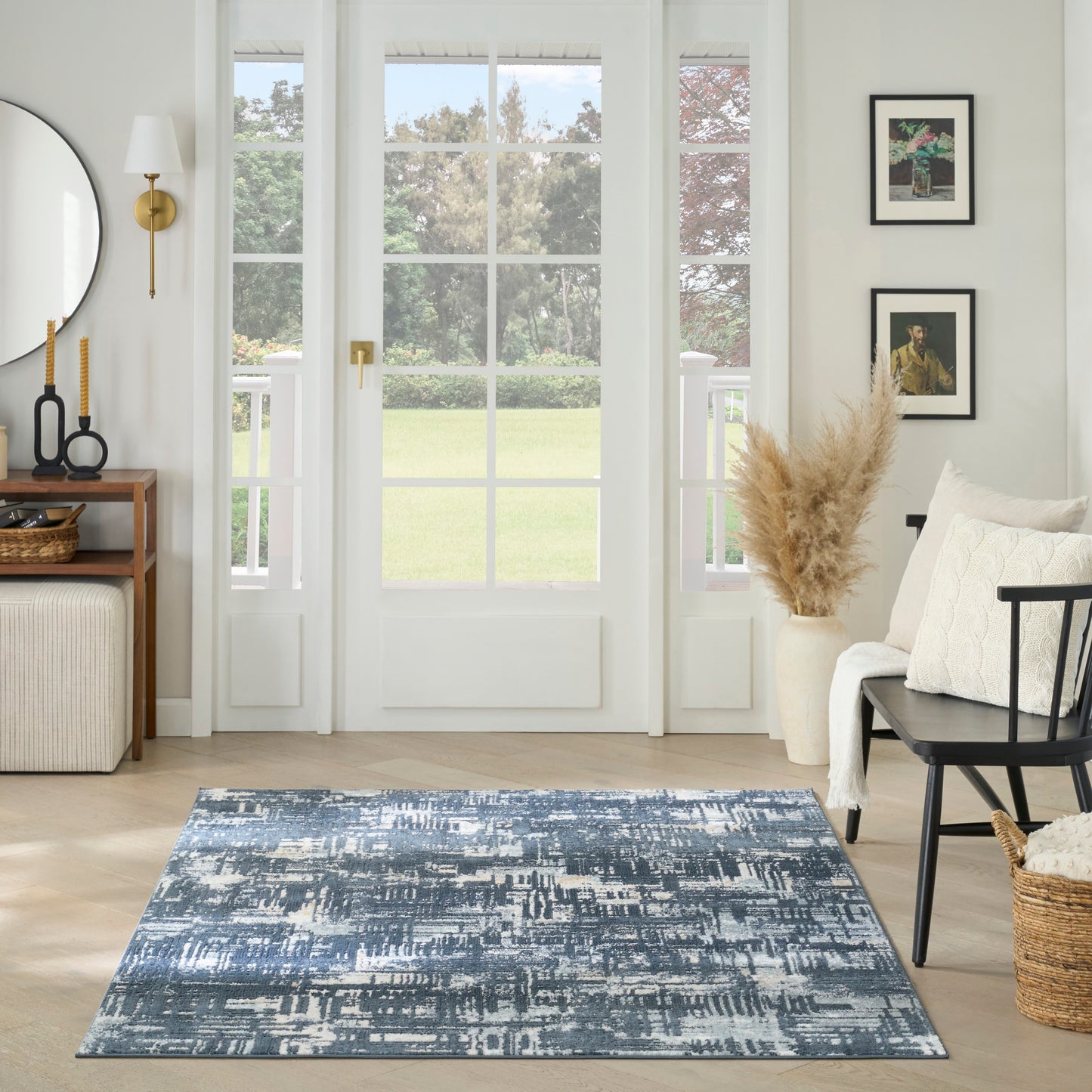 Bright living room with blue abstract rug, light wood floors, white French doors, neutral seating, pampas decor.