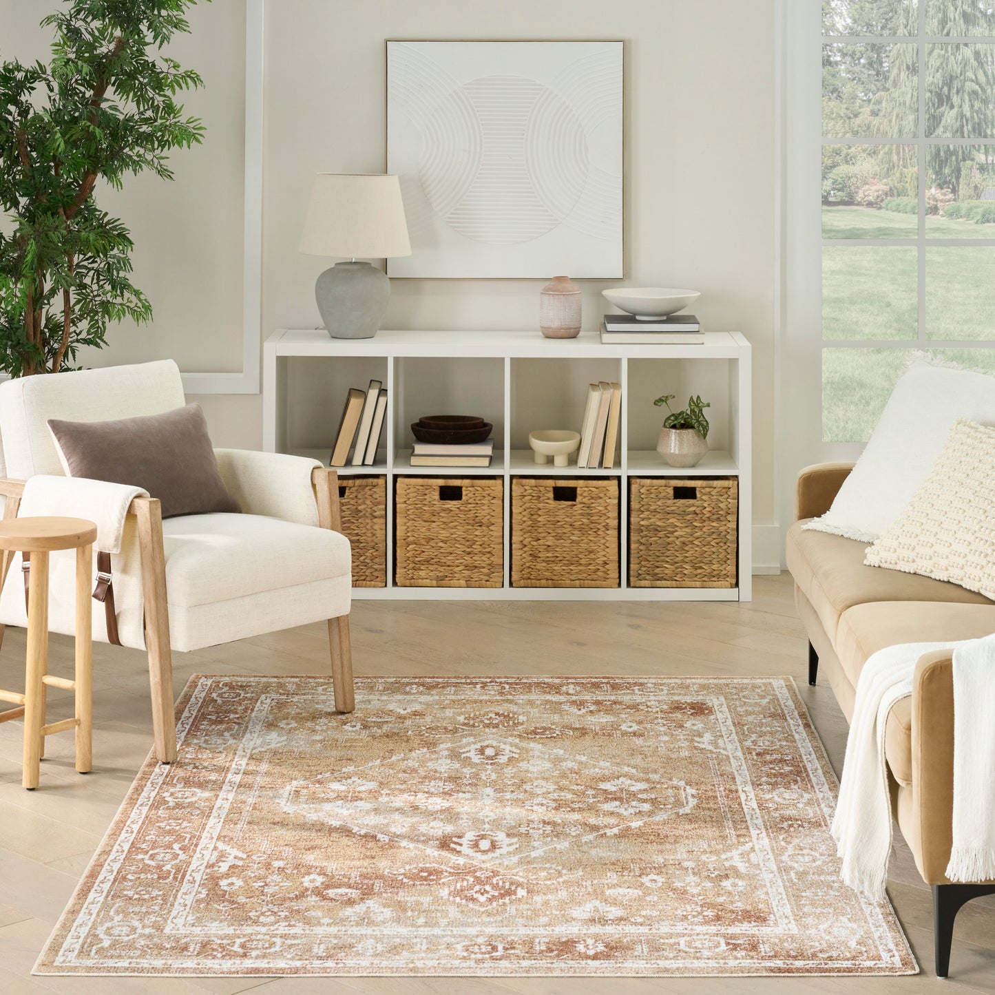 Peach and cream patterned area rug in a bright neutral living room with white storage cubby, beige chairs and greenery.