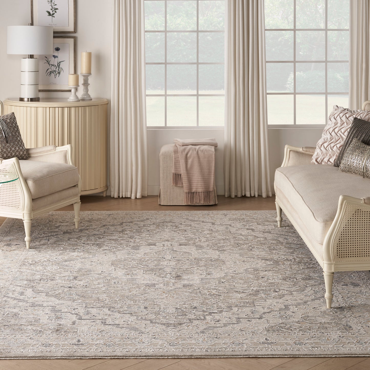 Neutral living room with cream wicker sofas, beige patterned rug, light wood console, sheer drapes and soft candles.