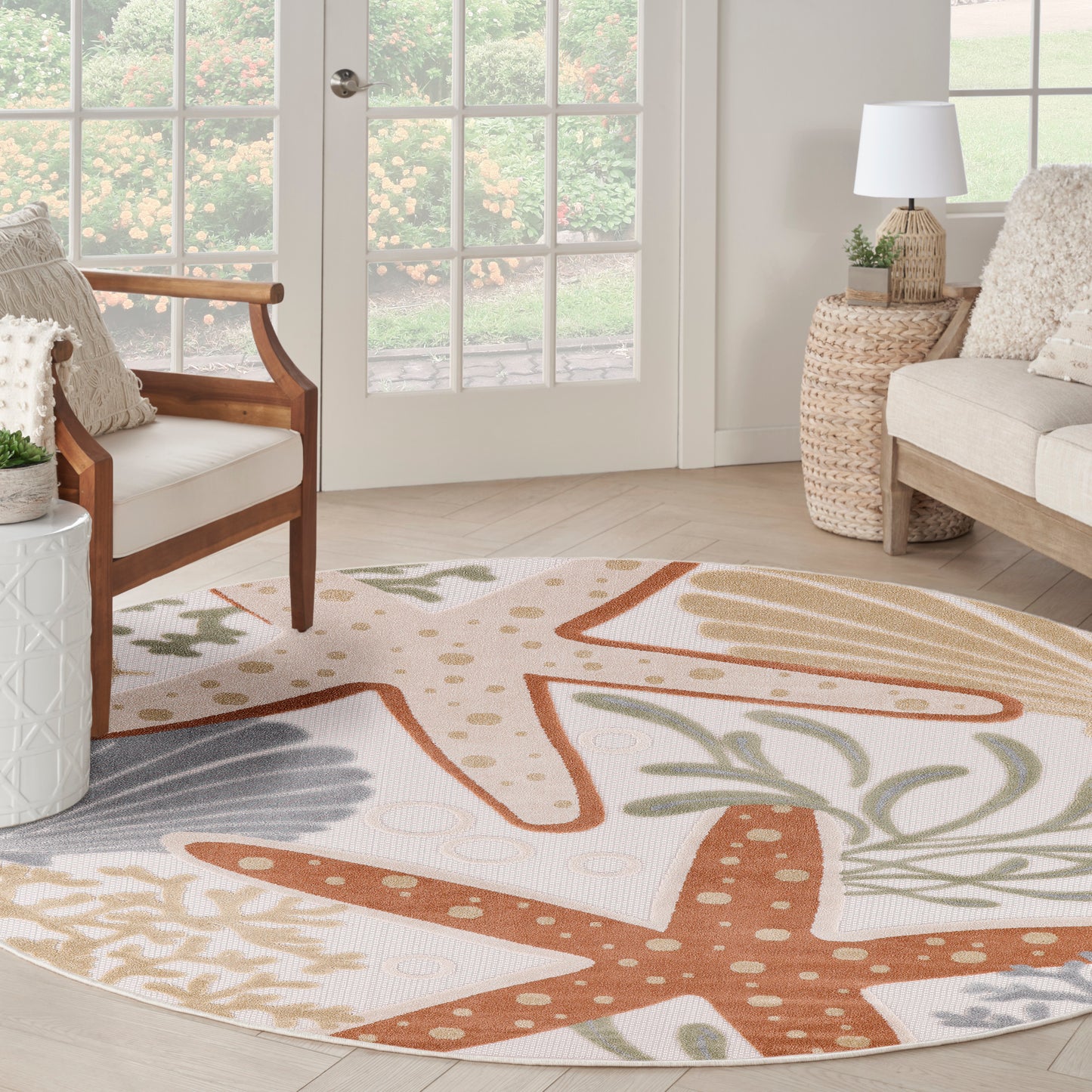 Round outdoor rug with orange starfish and palm leaf patterns on a cream background.