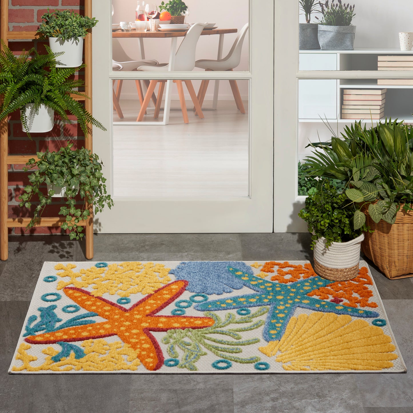 Coastal rug with colorful starfish and sea life in yellow, orange & blue on a white background.