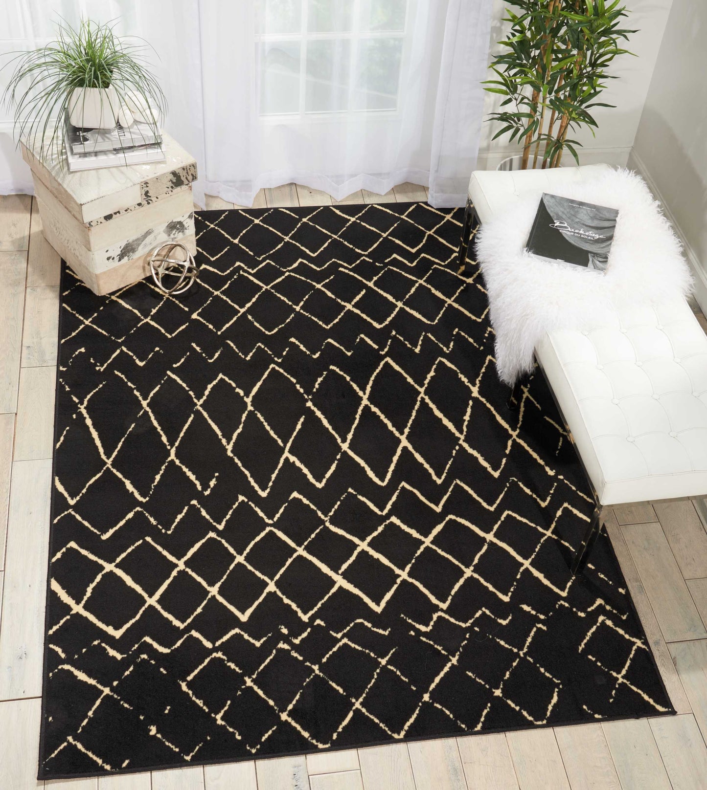 Black area rug with cream lattice pattern in a bright living room, paired with a white tufted bench and greenery.