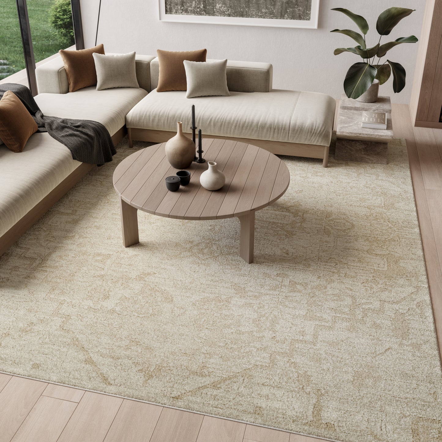 Neutral living room with round wooden coffee table, beige sectional, brown/taupe cushions, textured beige rug, plant.