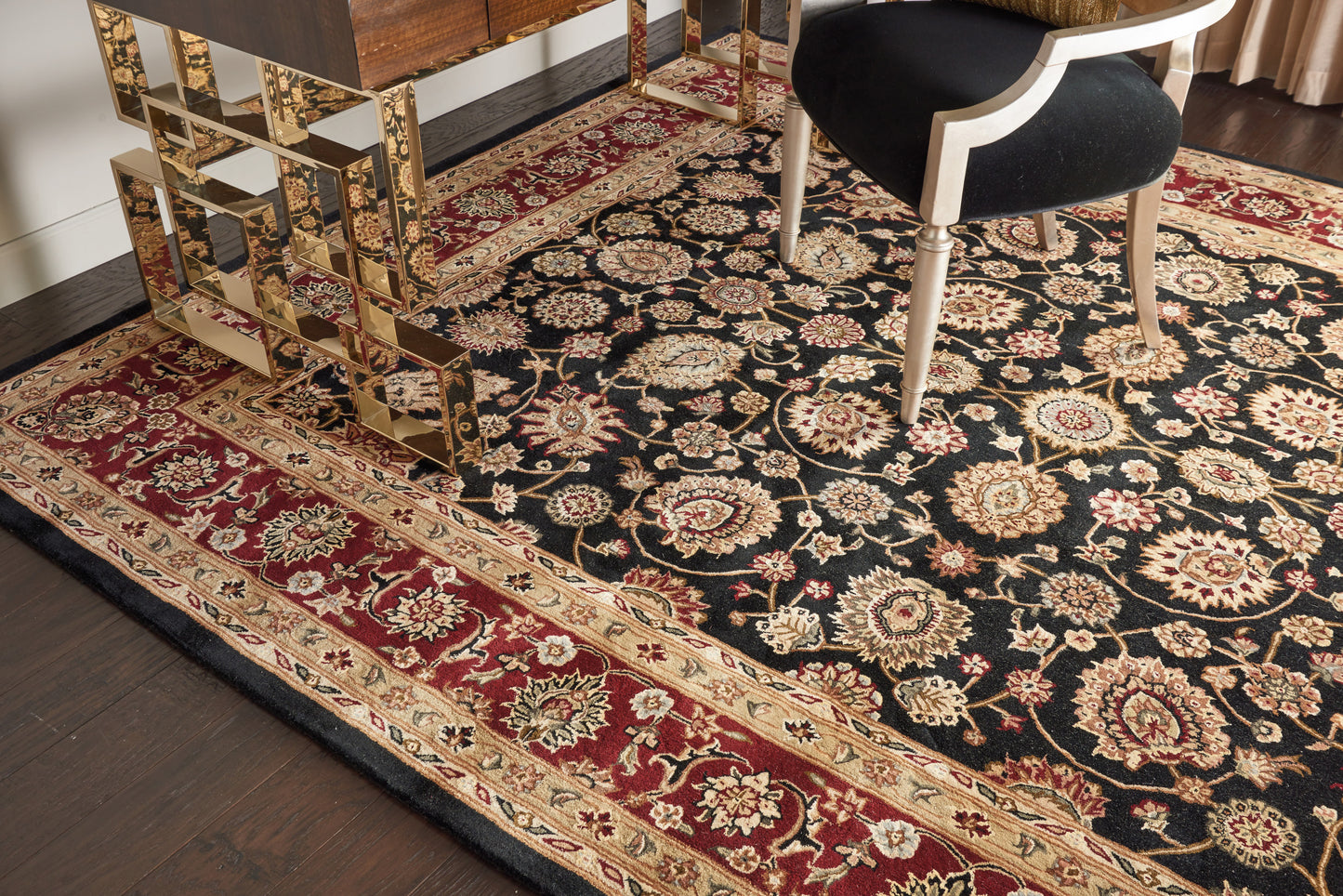 Persian-style oriental area rug with black field, ivory/gold floral motifs and a red border.
