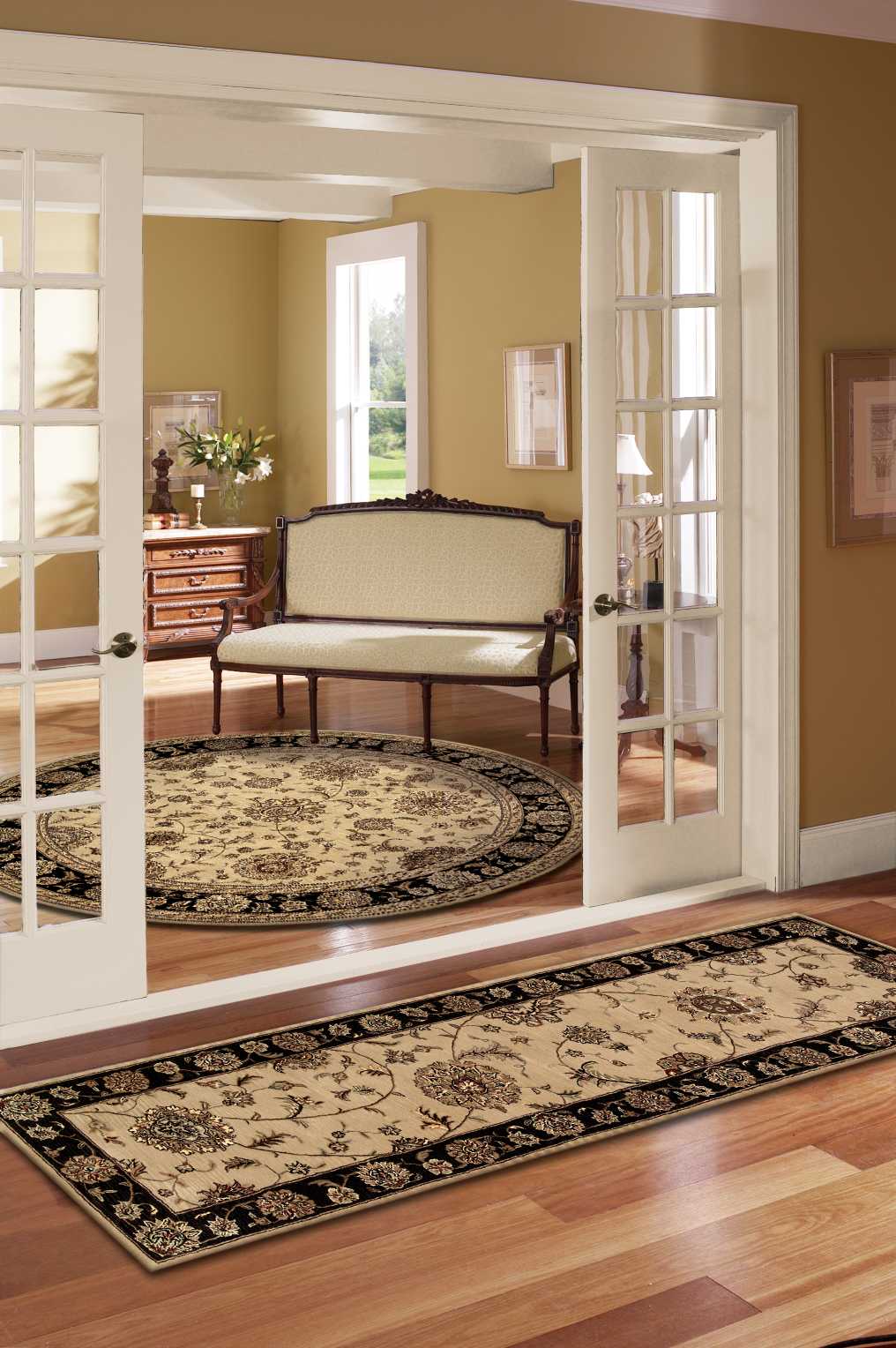 Ivory ornate Oriental rug with black border and floral motif; warm foyer scene with French doors and vintage furniture.