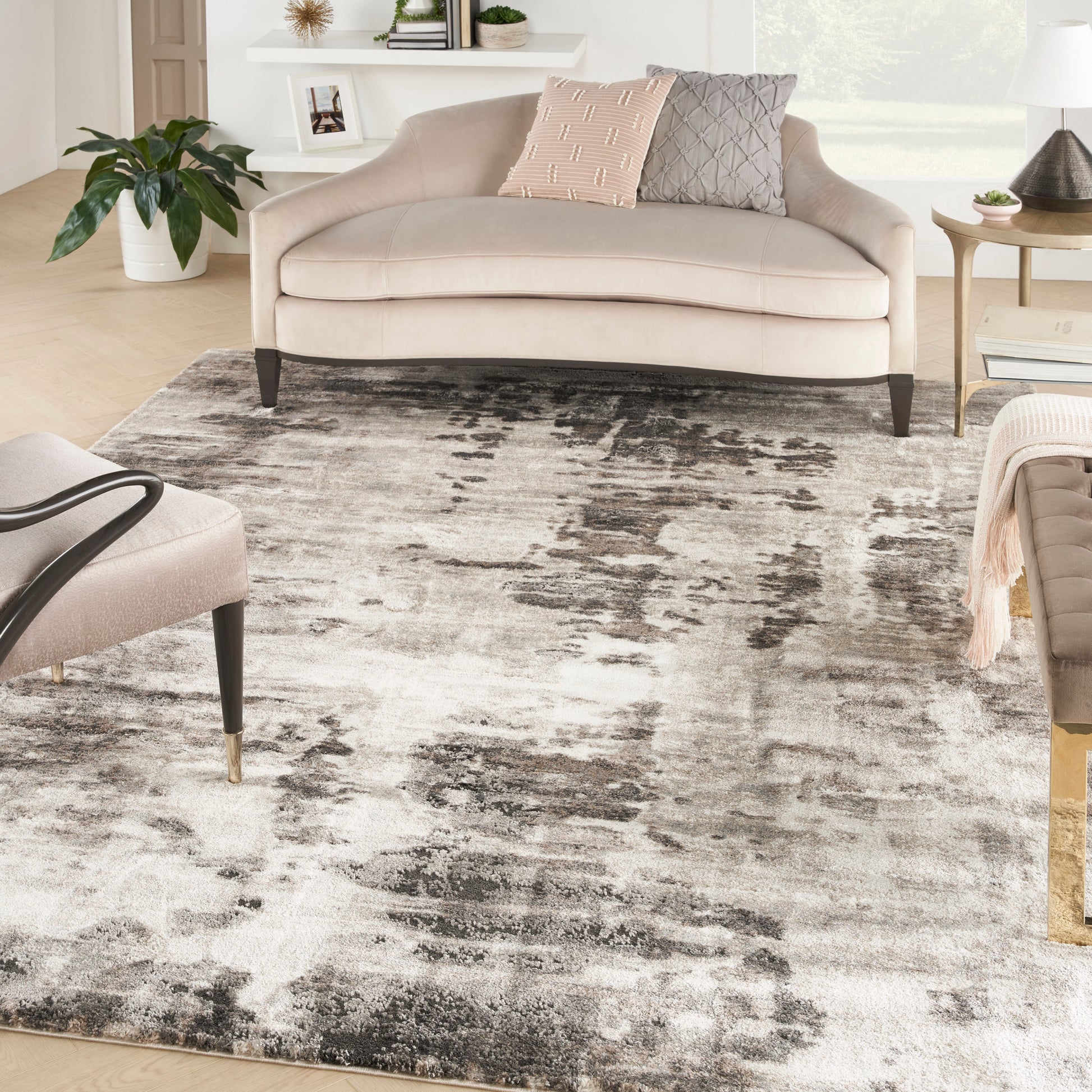 Gray abstract rug in a bright living room with a beige curved sofa and pink and gray pillows nearby