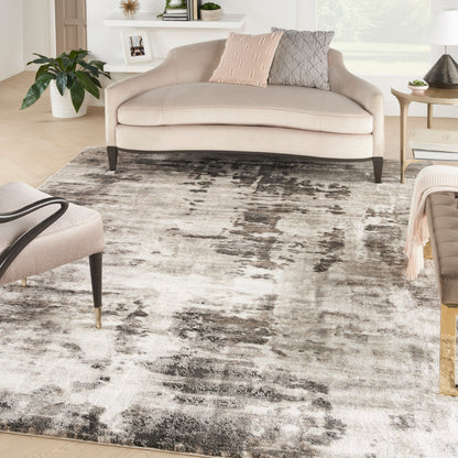 Gray abstract rug in a bright living room with a beige curved sofa and pink and gray pillows nearby