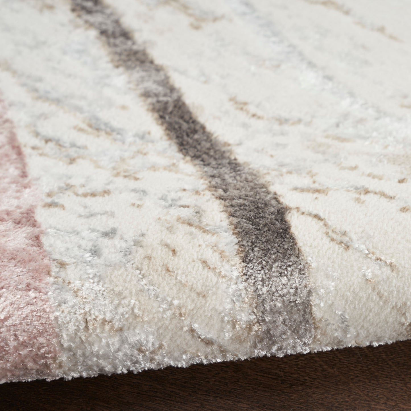 Close-up of a plush cream area rug with pink and gray stripes and soft textured pile.