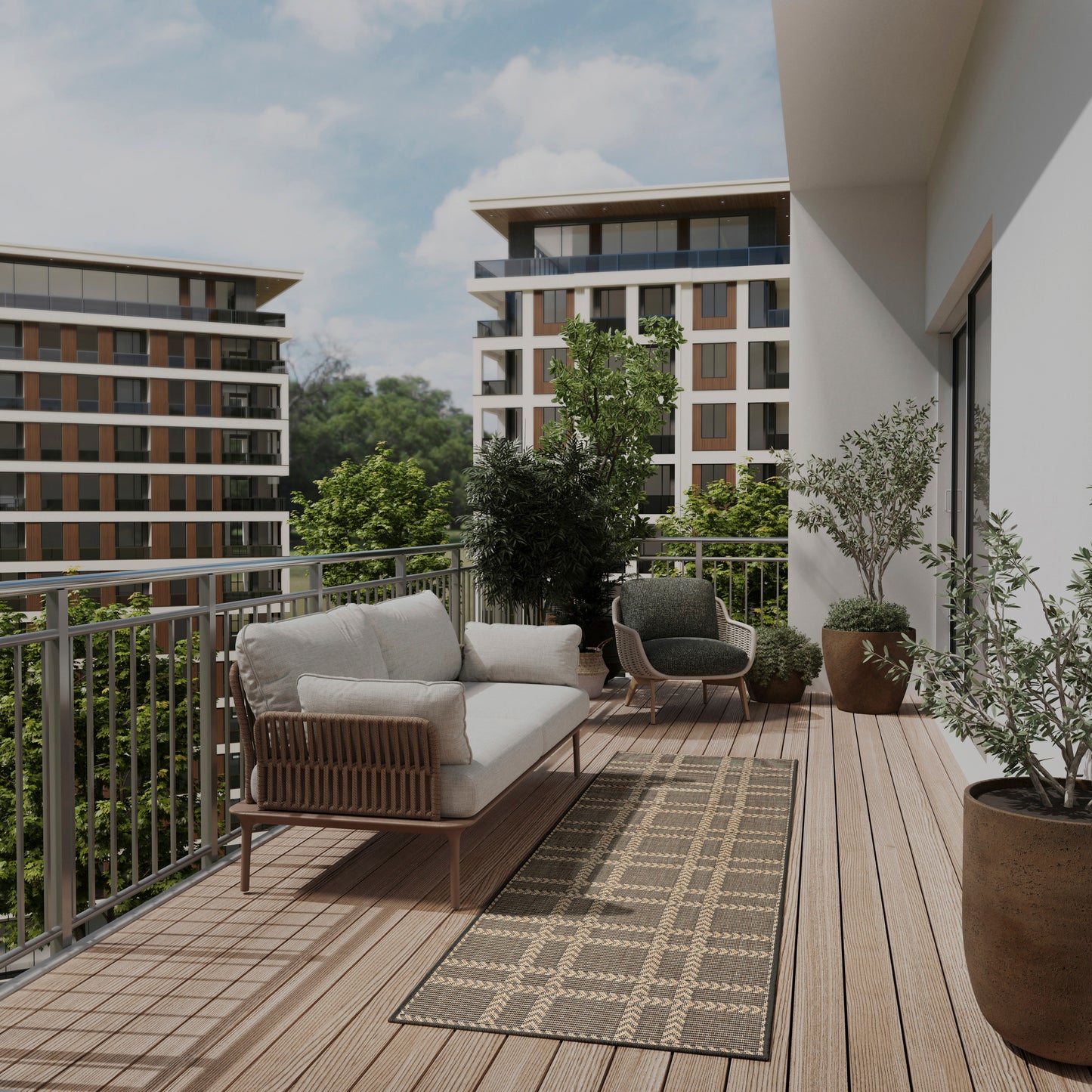 Modern balcony with wooden decking, beige cushioned wicker sofa, round armchairs, grey patterned rug, and potted plants.
