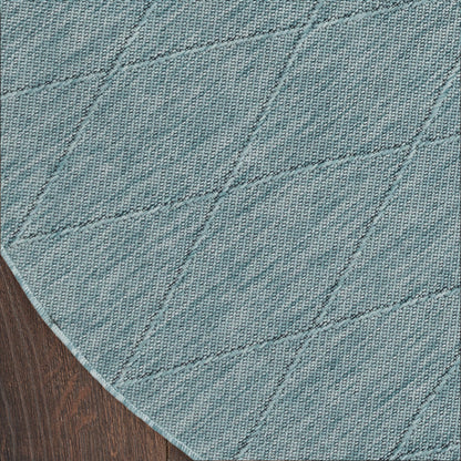 Teal woven round rug with diagonal diamond stitching on dark wood floor.