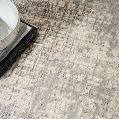 Beige-gray textured area rug with abstract pattern; white ceramic bowl atop stacked dark books.