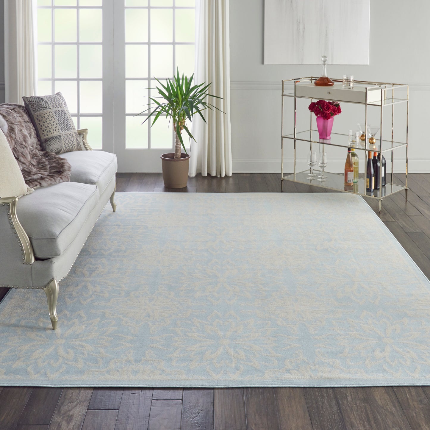 Rectangular light blue area rug with subtle ivory floral pattern in a chic living room.