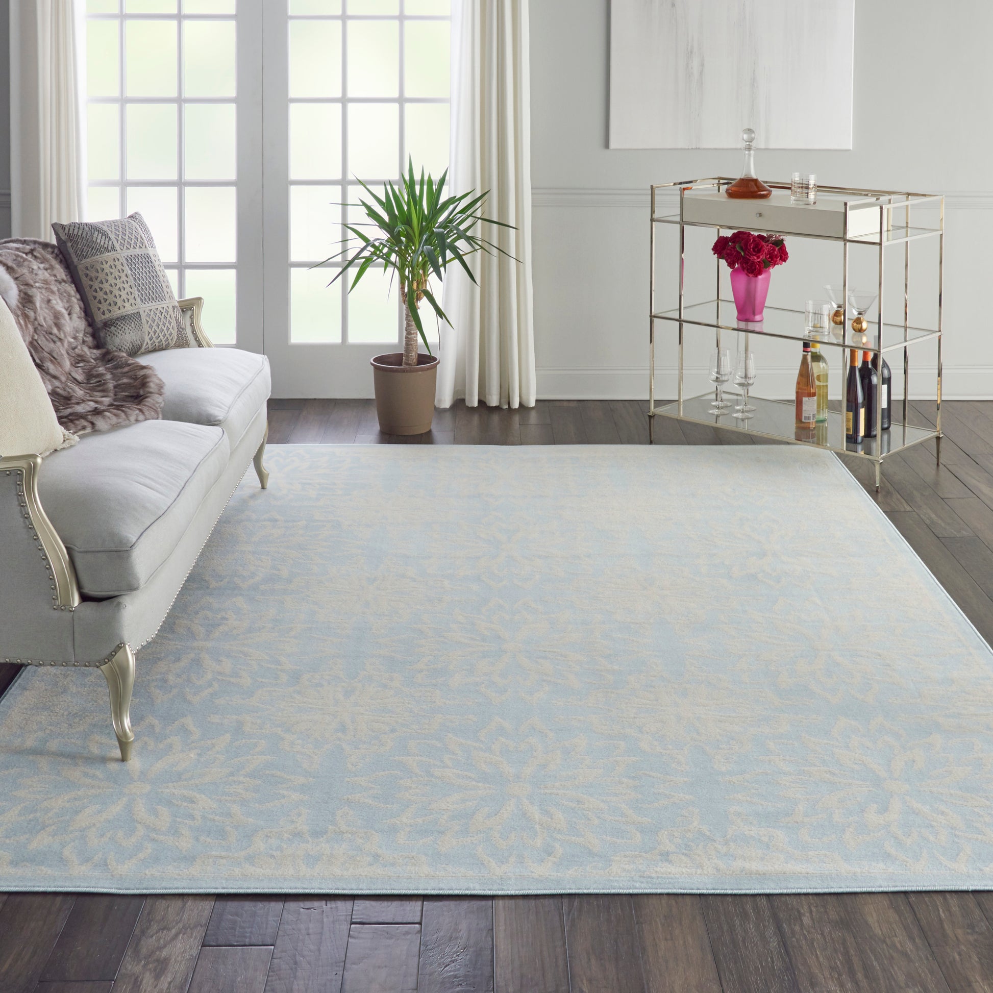 Rectangular light blue area rug with subtle ivory floral pattern in a chic living room.
