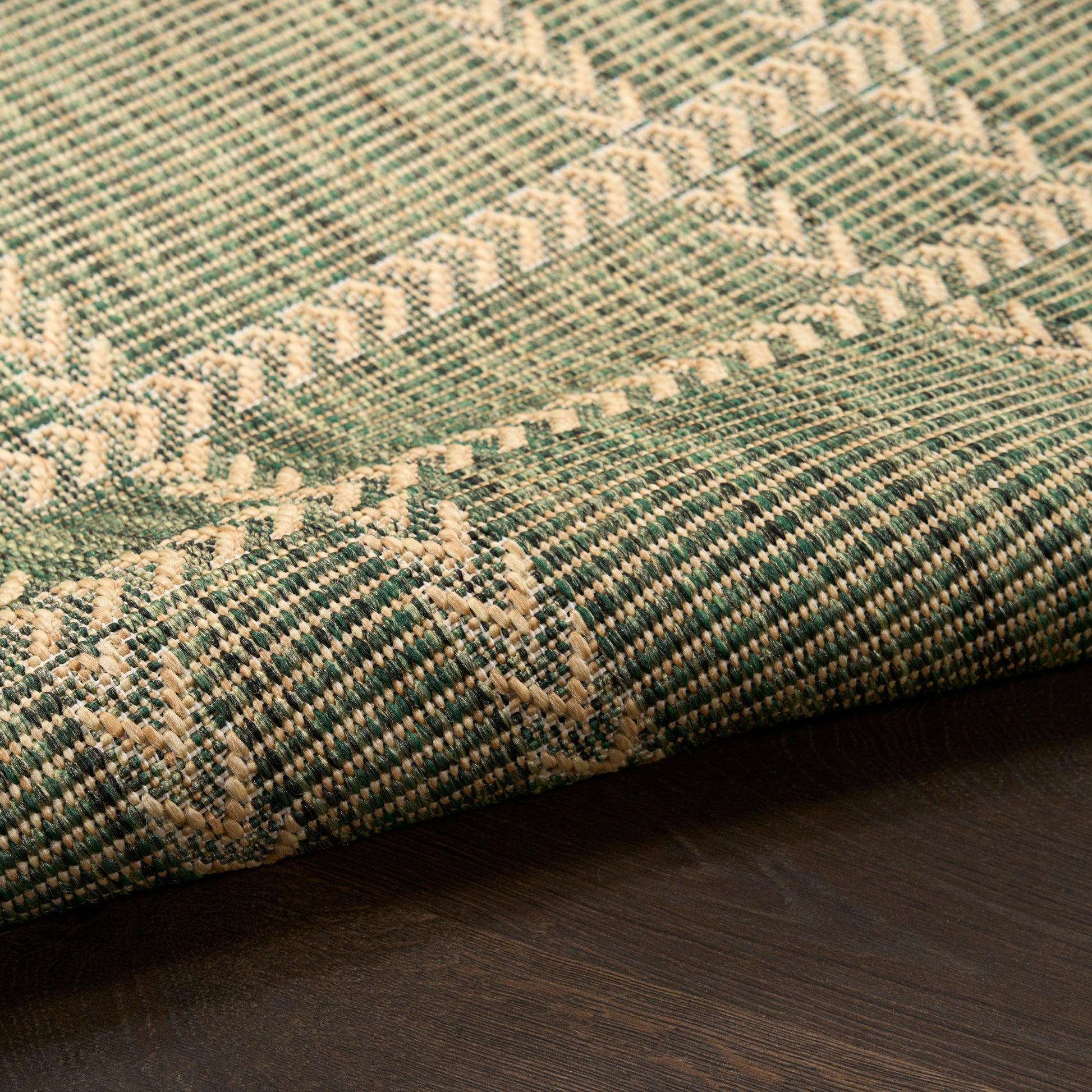 Teal and ivory geometric woven rug with diamond and chevron pattern on dark wooden floor.