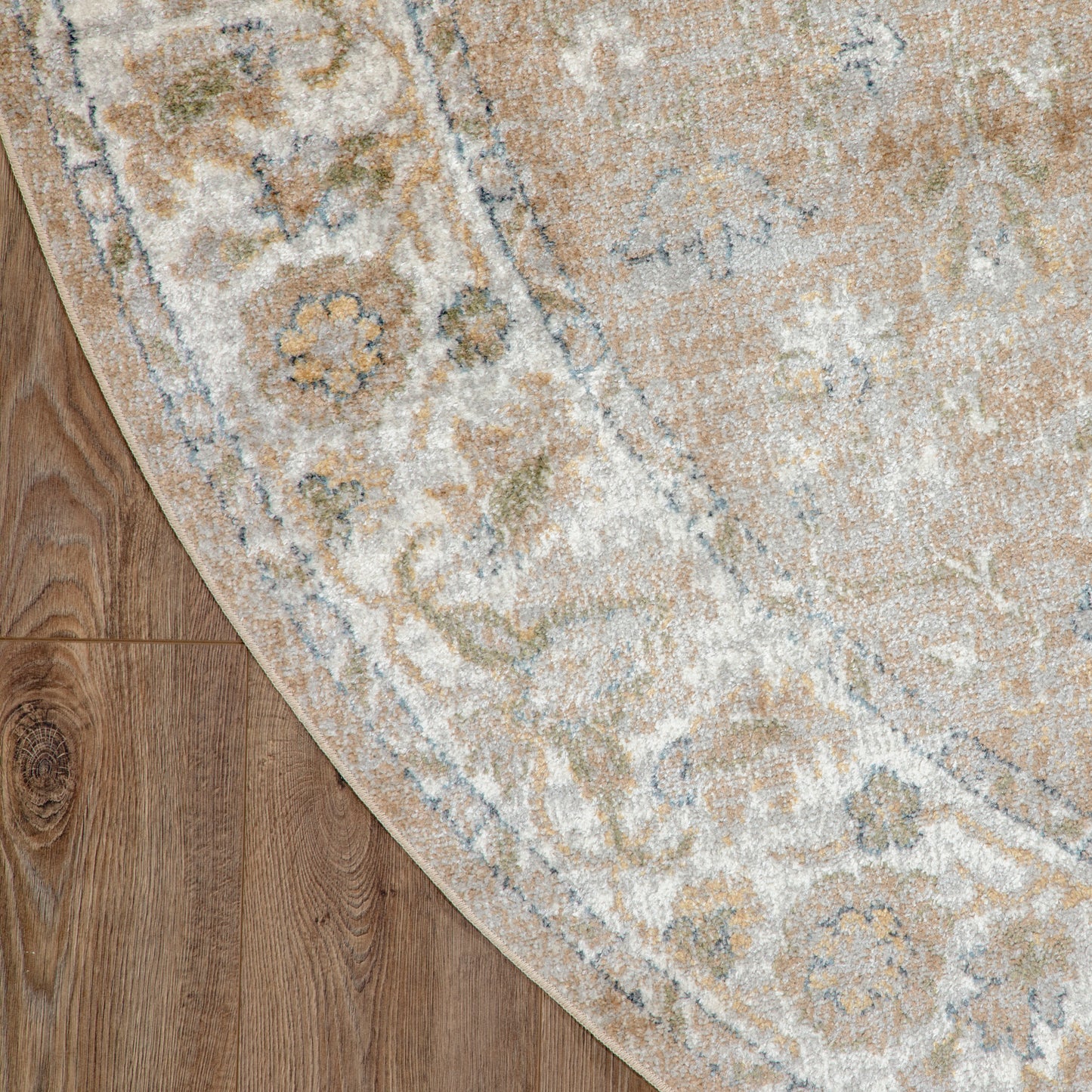 Round area rug with traditional floral medallion pattern in beige, ivory and pale blue on a wooden floor.