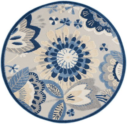 Round rug with blue, ivory and gray floral pattern, bold central bloom, dark blue border.