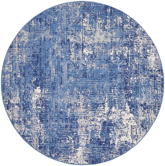 Round blue abstract-pattern rug with distressed vertical blocks in navy, light blue, and ivory.