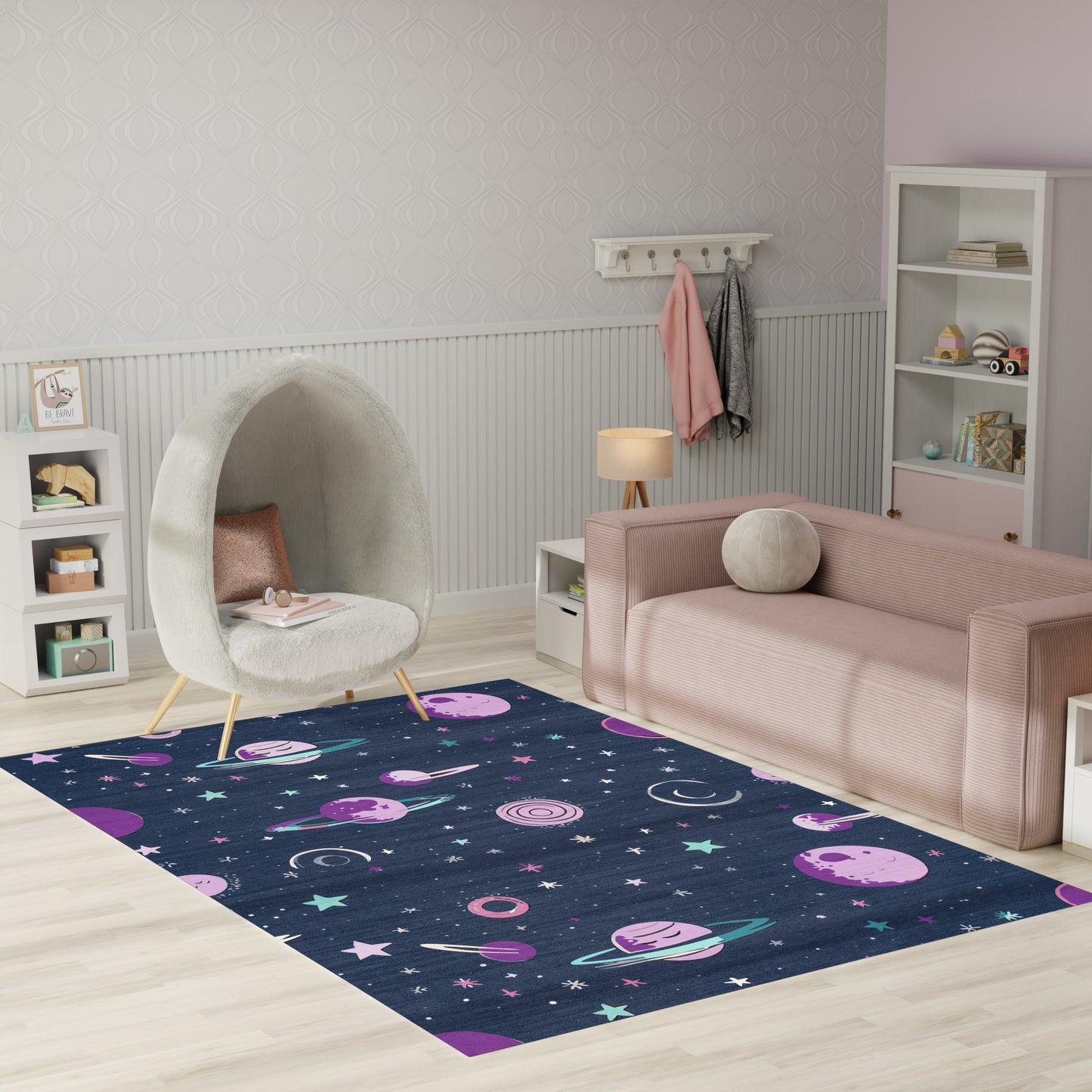 Space-themed navy rug with pink planets and stars in a kids' playroom, pastel pink sofa and white egg chair.
