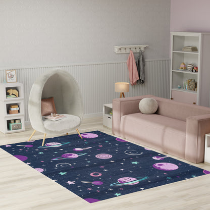 Space-themed navy rug with pink planets and stars in a kids' playroom, pastel pink sofa and white egg chair.