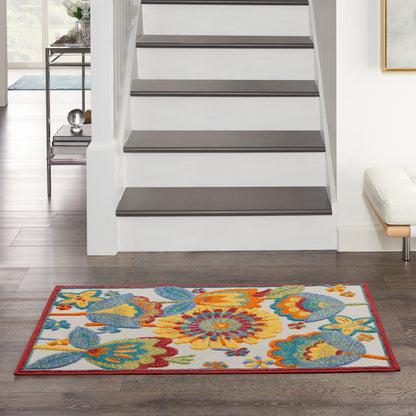Rectangular floral area rug with orange, yellow, blue blooms & red border at the base of a staircase in a living room.