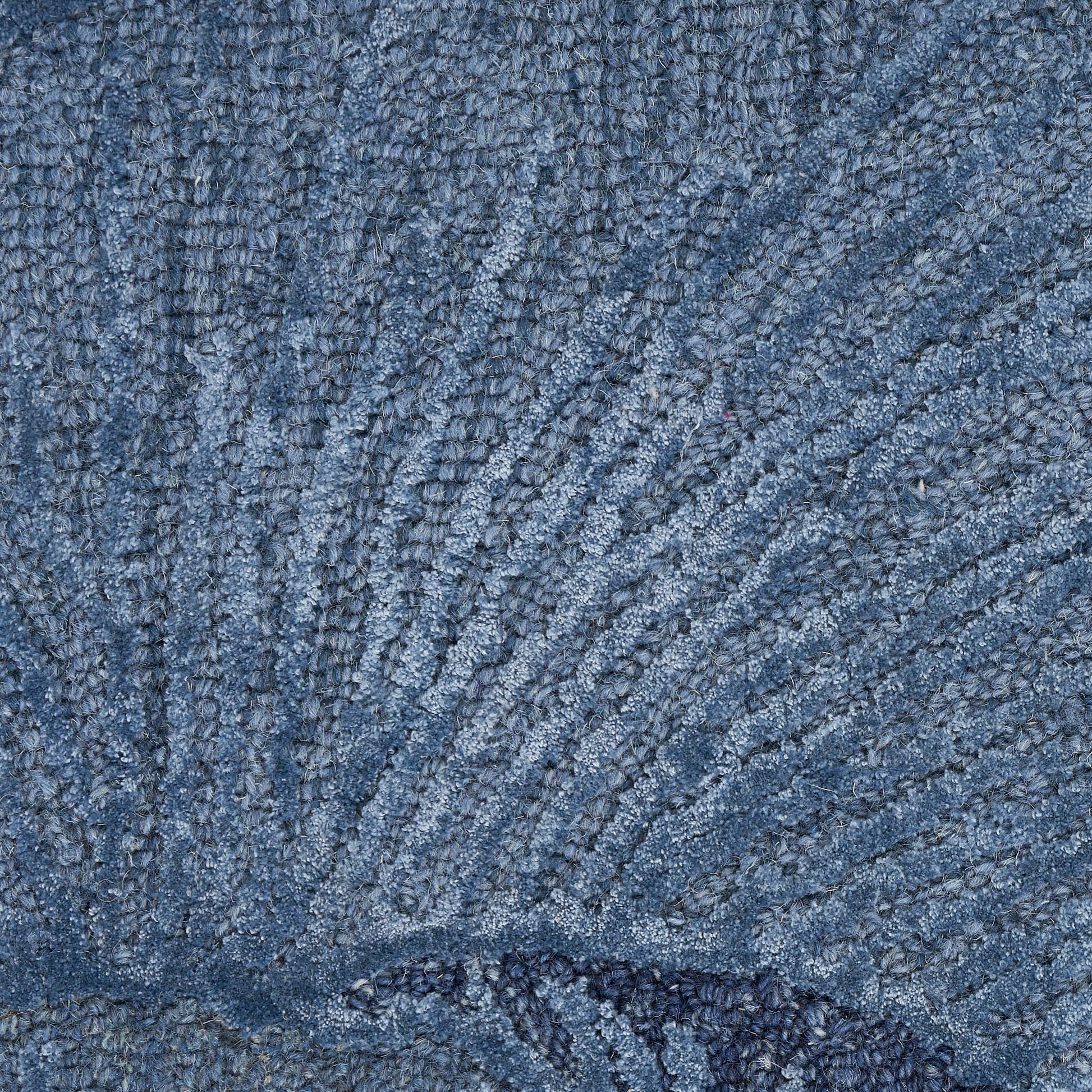 Close-up of blue rug fabric with looped pile and edge seam.