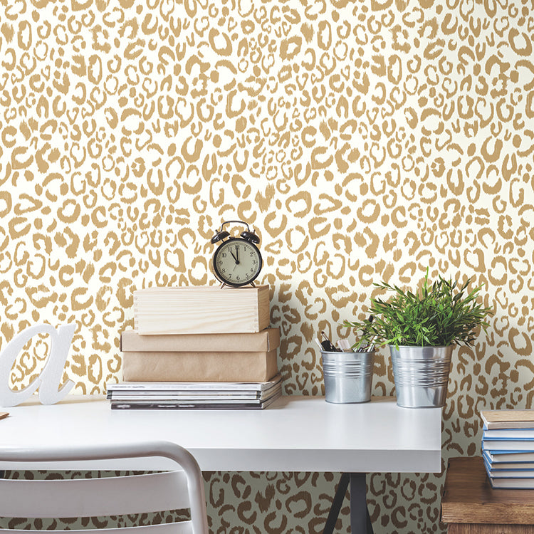 Gold leopard-print peel-and-stick wallpaper roll (RMK10700WP) displayed on a wall, showing metallic gold animal-print pattern — perfect for bold, glam interiors.