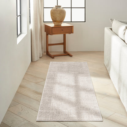 Light beige runner rug on pale wood floor, beside a wooden side table with a ceramic vase, in a sunlit neutral living room.