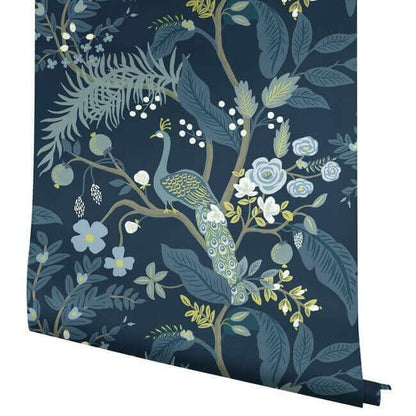 Rifle Paper Co. Peacock Wallpaper in Navy featuring graceful peacocks surrounded by flowering branches, vibrant blossoms and layered emerald foliage. This detailed floral and bird wallpaper creates a sophisticated garden-inspired backdrop for bedrooms, dining rooms, living rooms and accent walls.